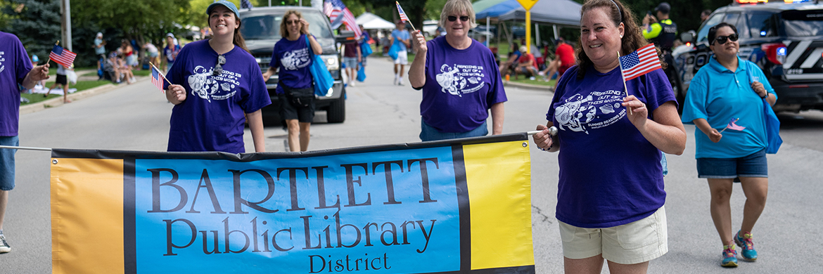 Group of attendees walking in the Fourth of July Parade with a Bartlett Public Library banner