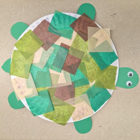 Turtle craft made from a paper plate covered in green and brown tissue paper squares.