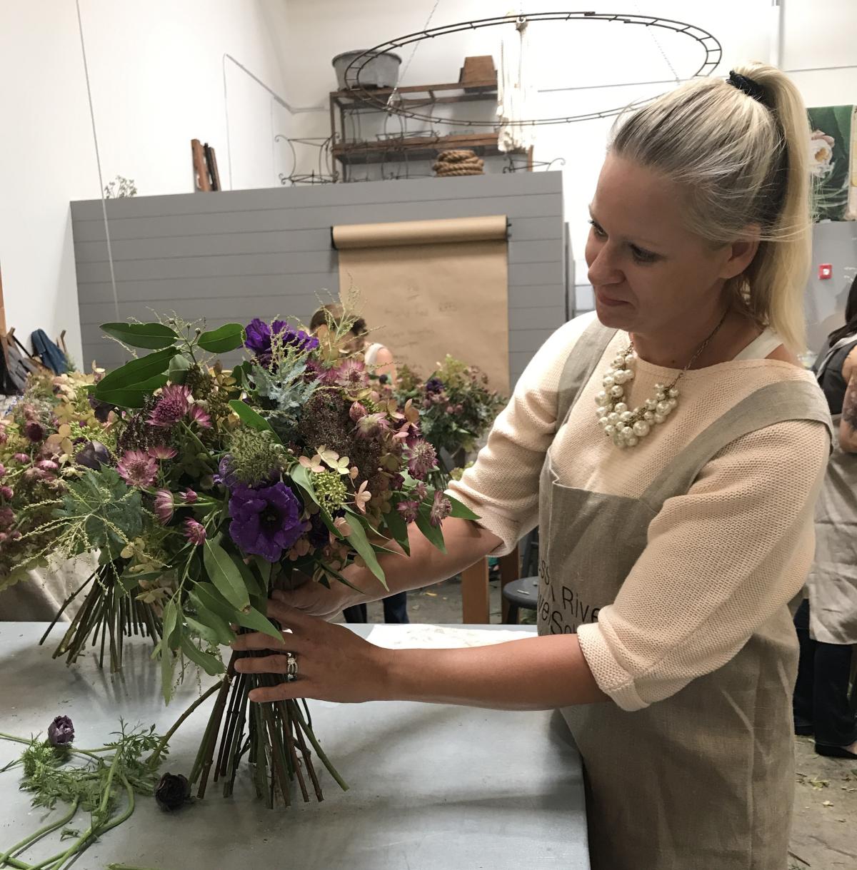 Heather Coughlin, of Pure Bloom Flowers, arranging flowers in a vase.