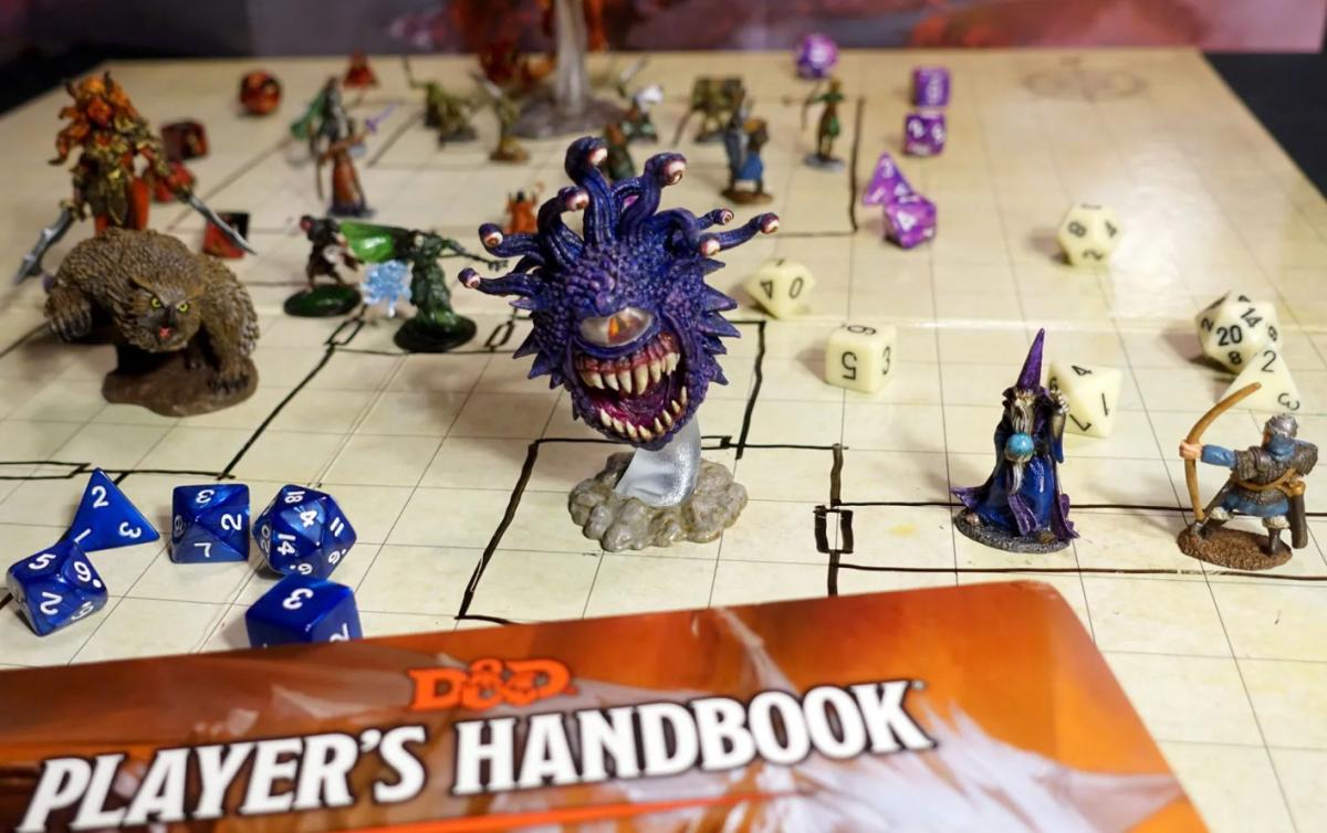 Dungeons & Dragons player's handbook on drawn map with mini figures of characters and monsters