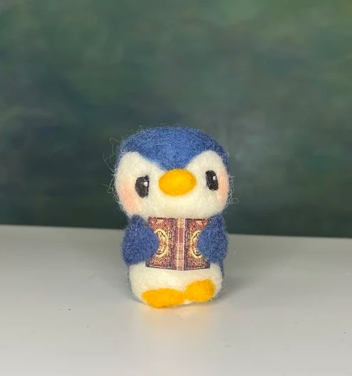 needle felted blue bird holding a small book