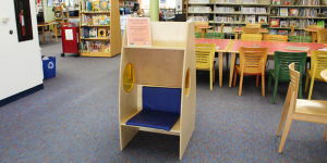 Single cabinet in the middle of the library. There are tables, chairs, and bookcases nearby.