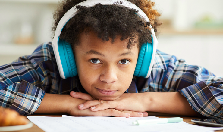 Young boy with noise-cancelling headphones on while doing homework