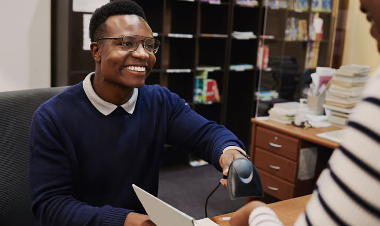 Male librarian scanning a book for a patron