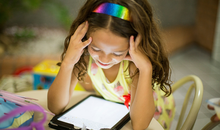 Girl smiling as she looks at her tablet screen