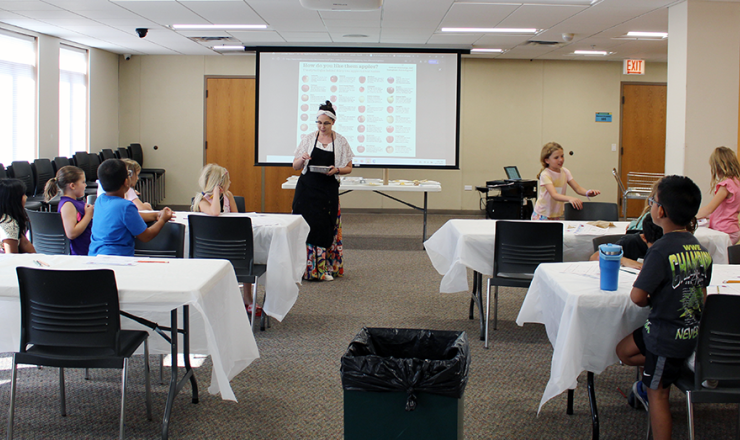 Librarian leading a hands on learning program with various children at tables
