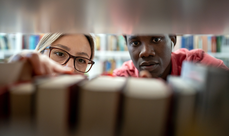 Man and woman looking at books on the library shelf