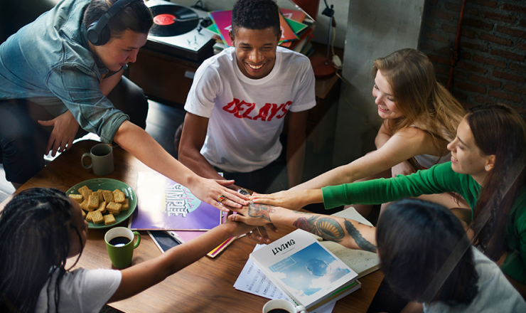 Group of six teens sitting around a table mid-discussion
